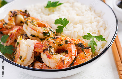 Grilled shrimps and boiled rice. King prawn tails in orange-garlic sauce with parsley.