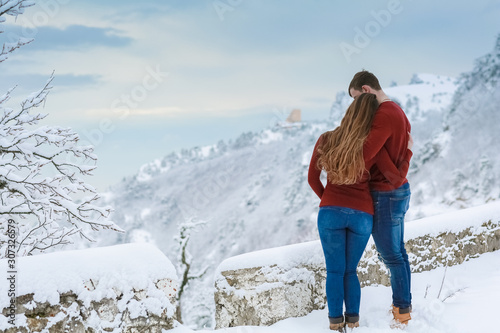 A man stands in warm clothes in winter and embraces a woman warming her with his warmth in cold weather.