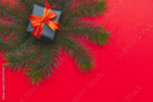 Blur background of top view of Christmas gift box red balls with spruce branches, pine cones, red berries and bell on red background.