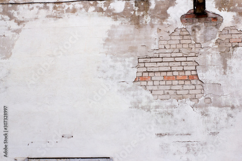 White brick plastered wall crumbling plaster, visible white and part of the red bricks