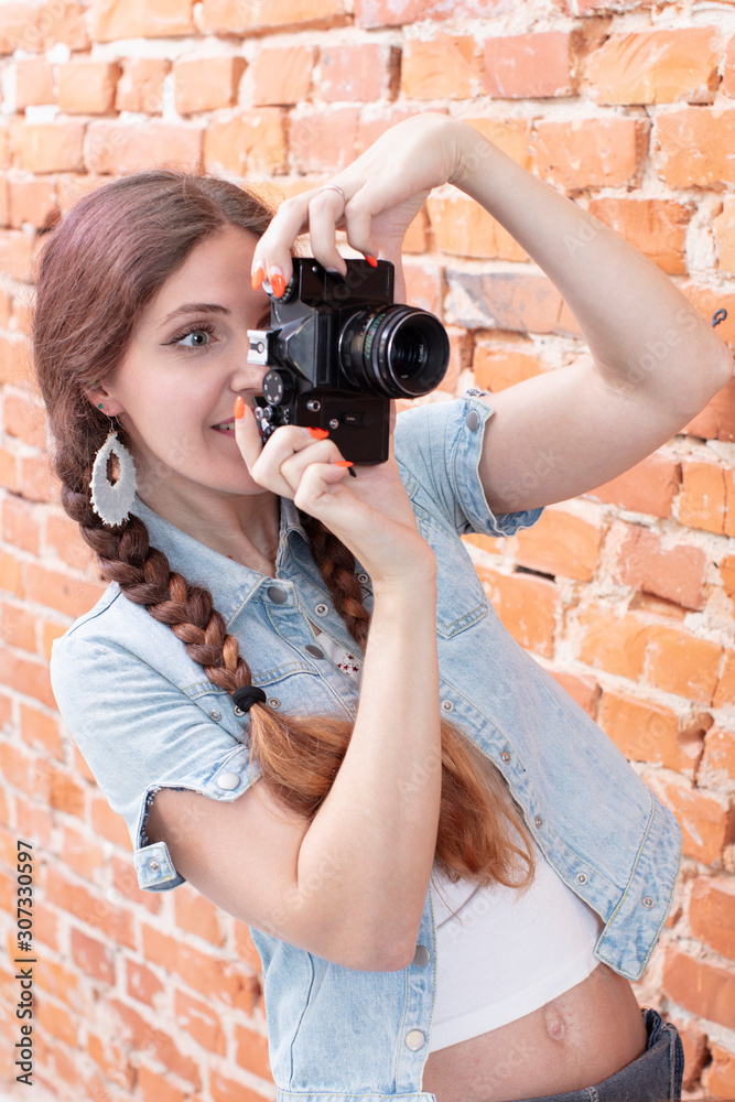 Vertical girl with a camera on a background of a brick wall