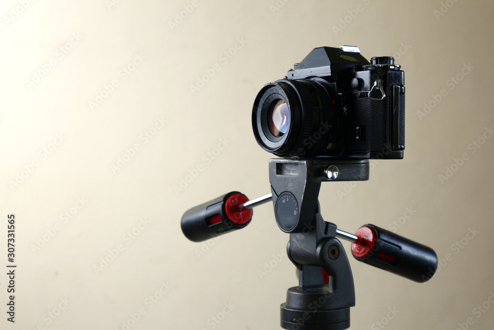 Old and vintage small format or 135mm film camera on a tripod. foto de  Stock | Adobe Stock