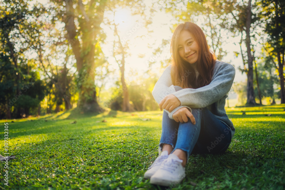 Portrait image of a beautiful asian woman sitting among nature in the park before sunset Portrait image of a beautiful asian woman sitting among nature in the park before sunset