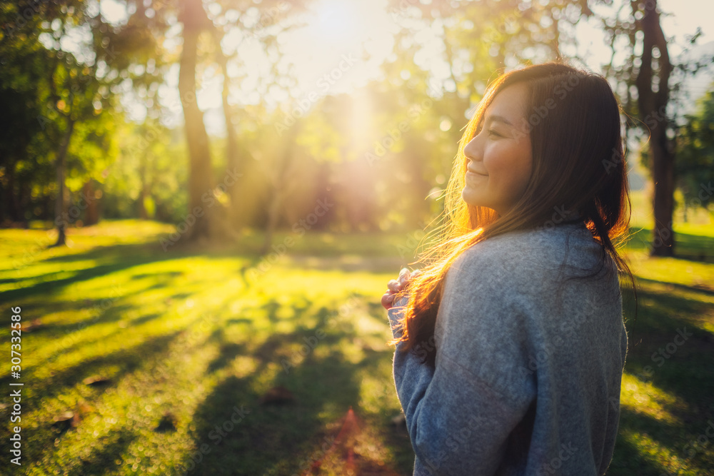Portrait image of a beautiful asian woman standing among nature in the park before sunset Portrait image of a beautiful asian woman standing among nature in the park before sunset