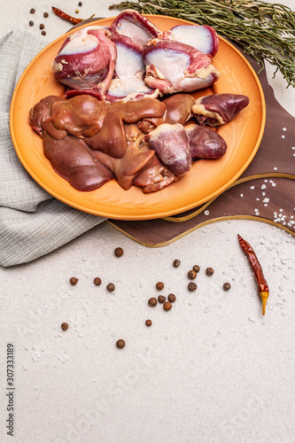 Fresh raw duck offal: heart, liver, stomach. Dry spices, salt, chili pepper. Wooden cutting boards, stone concrete background photo