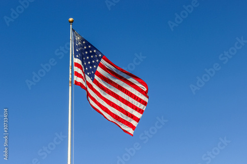 Large American flag waving in the wind with a blue sky background, Ellis Island near The Statue of Liberty, New York