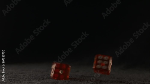 Two red dice thrown on a black casino table they are slowly turning in the air falling and rolling on the table in slow motion rolled a five and a three translucent red color illuminated Full HD 1080p
