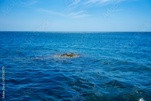 Seascape with a small rock on the background of water