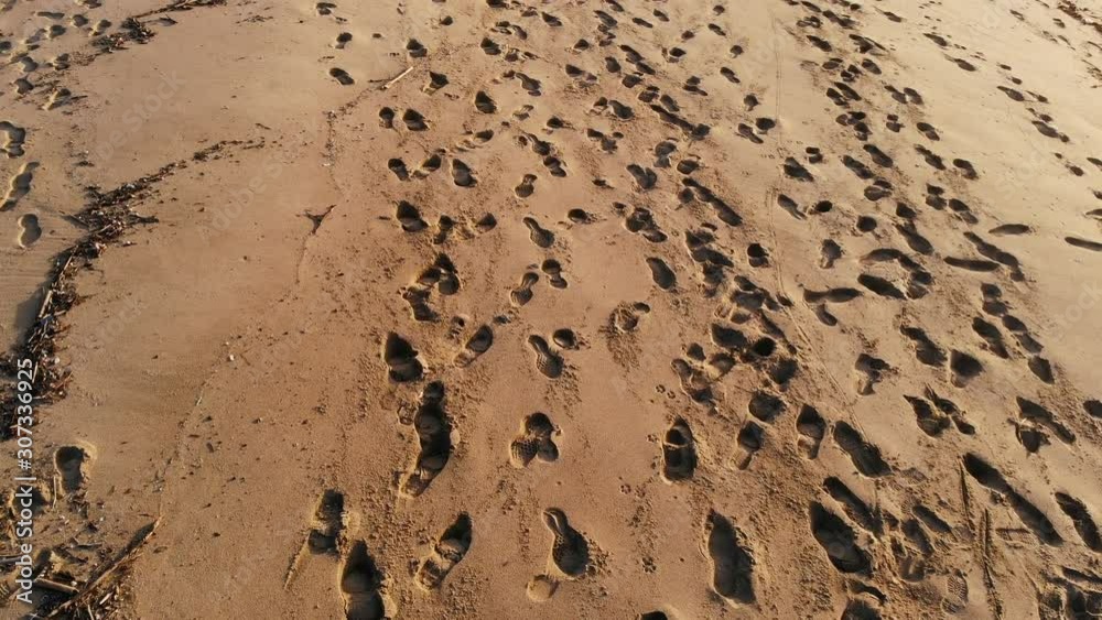 Aerial flying view above Human footprints on orange sandy sea beach,ecosystem 4k