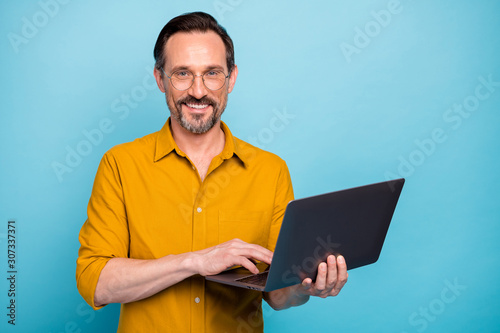 Portrait of positive cool mature man hold his computer work text type chatting with family colleagues wear good looking clothes isolated over blue color background