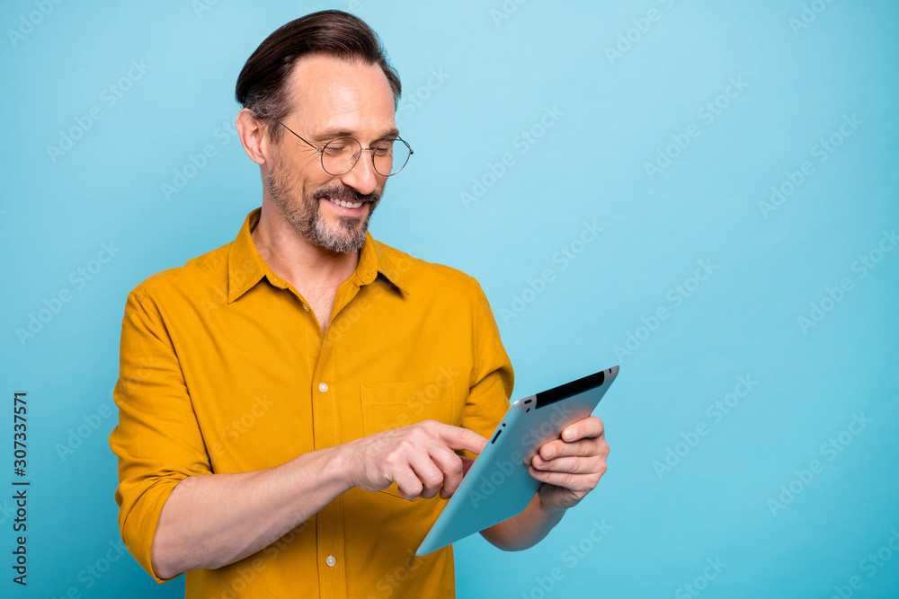 Turned photo of positive cool man tablet user search social media information feel dreamy glad expression wear stylish clothing isolated over blue color background - obrazy, fototapety, plakaty 
