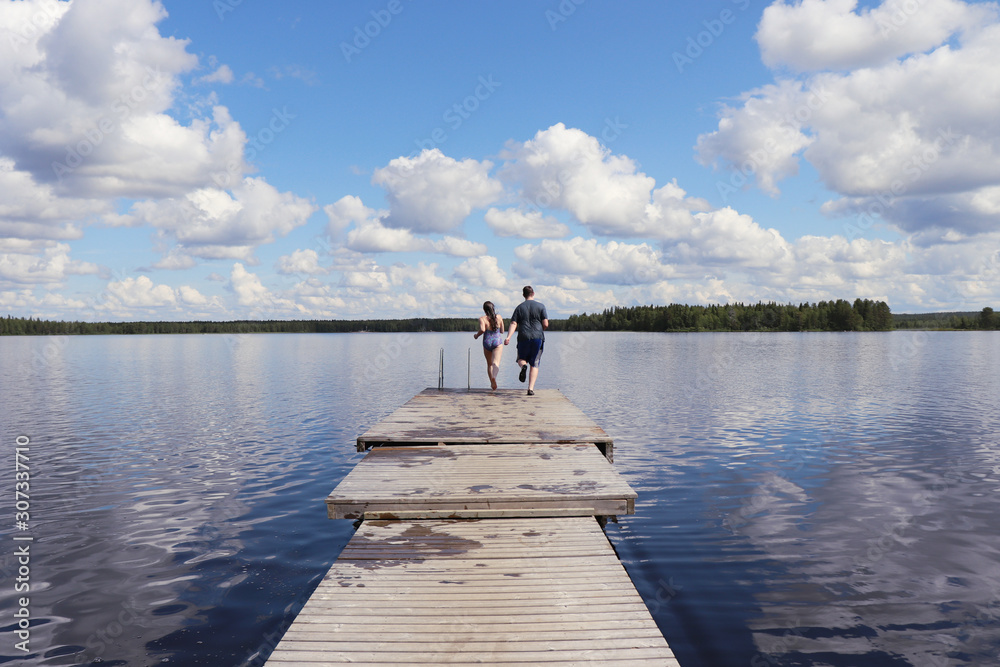 Two kids running to the end of a dock at Lake Ranuanjarvi in Finland