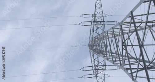a german transmission tower electricity pylon power pole with insulators and cables  filmed from bellow panned camera cloudy sky in the background standing right under the pylon 4K high quality