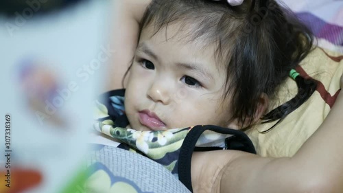Little Asian baby girl, 2 years old, enjoyed listening to her mother reading aloud a bedtime story from a book