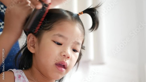 Little baby girl, 41 months old, sitting in front of her mother and let her mom doing her hair early in the morning