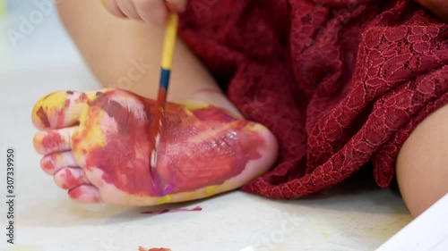 Closeup of a little baby girl's foot being painted by herself at home - baby handprint / fingerprint / footprint painting