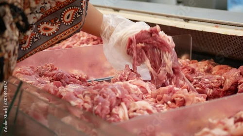 Pieces of pork in tray for sale being selected / picked by a woman, a customer - self service retail butchery