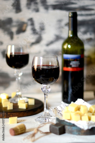 Red wine in glasses and cheese on a white wooden background