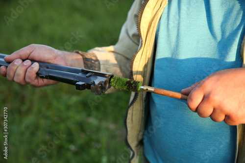 hunter's hands clean the rifle with a ramrod