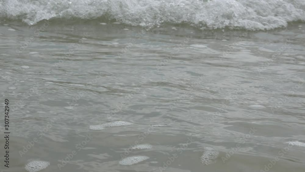 Wavy seawater surface, selective focus and closeup, at the beachside