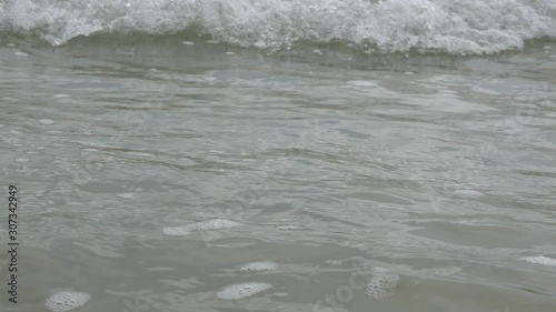 Wavy seawater surface, selective focus and closeup, at the beachside
