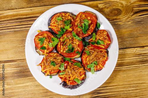 Baked eggplants with tomatoes and cheese on wooden table. Top view