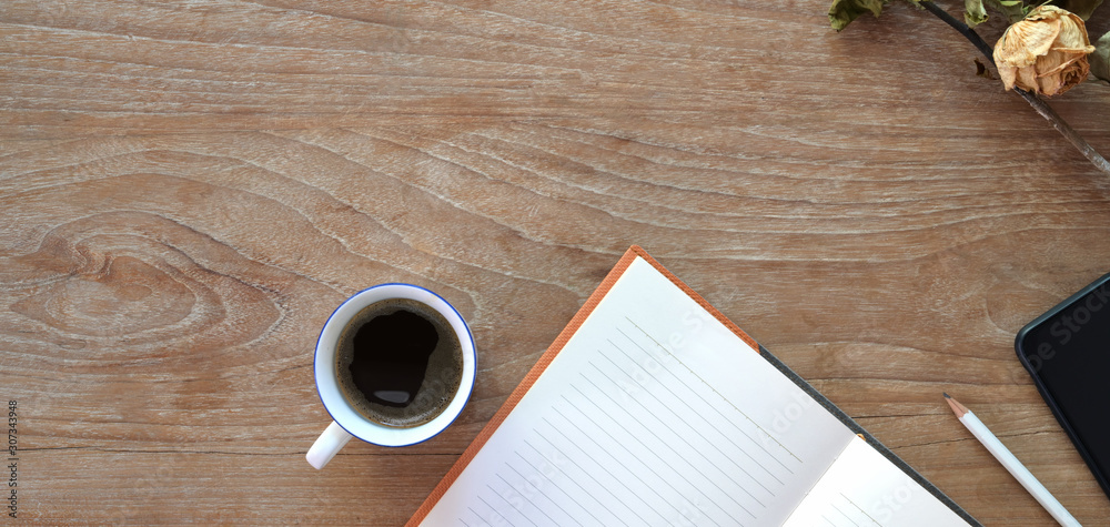 Top view of comfortable workplace with open notebook, coffee cup and copy space on wooden table Top view of comfortable workplace with open notebook, coffee cup and copy space on wooden table