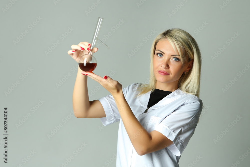 female lab technician in a white coat holding a flask with a reagent female lab technician in a white coat holding a flask with a reagent