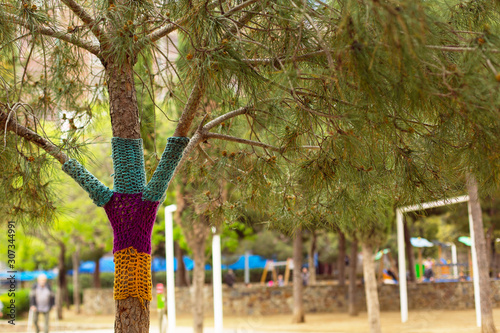 The trunk of a tree in a park tied up with yarn. Concept about a care of nature.