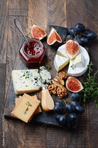 Cheese plate with grapes, figs, crackers, honey, plum jelly, thyme and nuts.