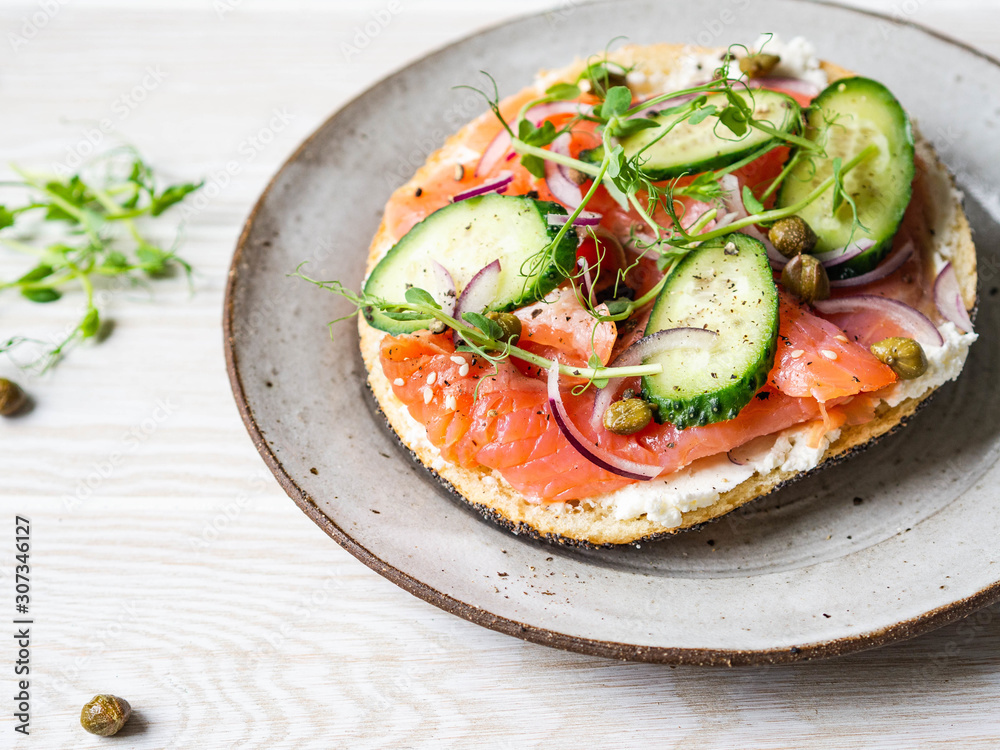 Healthy toast with cream cheese, salmon, fresh cucumber, capers, red onion, black pepper and pea sprouts on plate. Healthy toast with cream cheese, salmon, fresh cucumber, capers, red onion, black pepper and pea sprouts on plate.