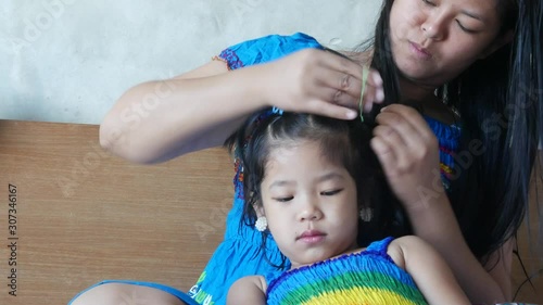 Little baby girl, 42 months old, sitting in front of her mother and let her mom doing her hair early in the morning