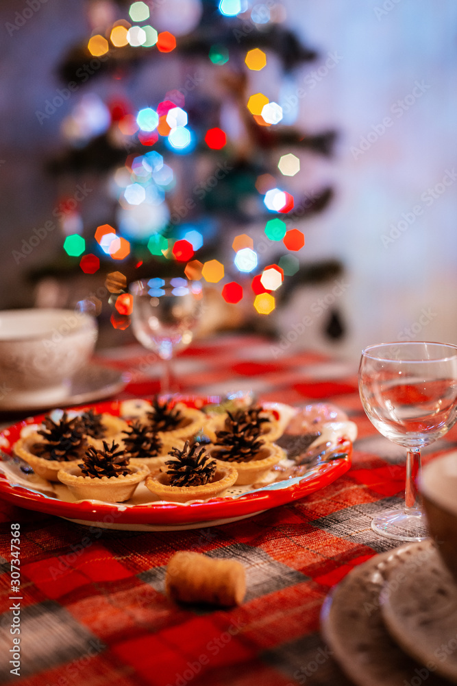 Traditionally decorated Christmas table. Creative decoration of the festive table cones on a plate on the background of bokeh lights.
