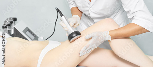 Cavitation rf body treatment. Female ultra sound lipo machine. Spa contouring. Doctor hands photo