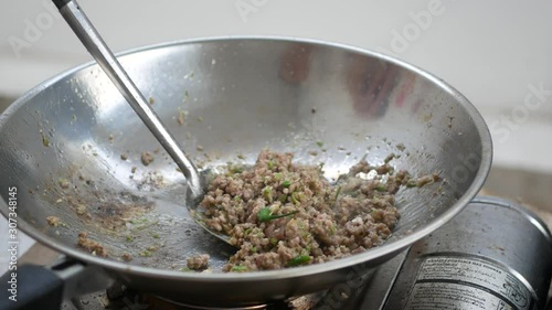 Minced pork with garlics and chilies being fried in a sizzling frying pan - cooking Pad Kra Pao, Holy basil with pork stir-fry, one of the most popular Thai a la carte dishes
