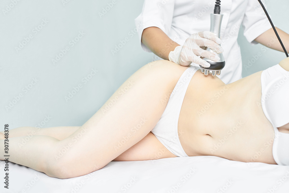 Fototapeta premium Perfect body radio treatment. Woman at spa procedure. Doctor hand and girl body. RF cosmetology lifting. Legs