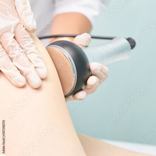 Cavitation rf body treatment. Female ultra sound lipo machine. Spa contouring. Doctor hands photo