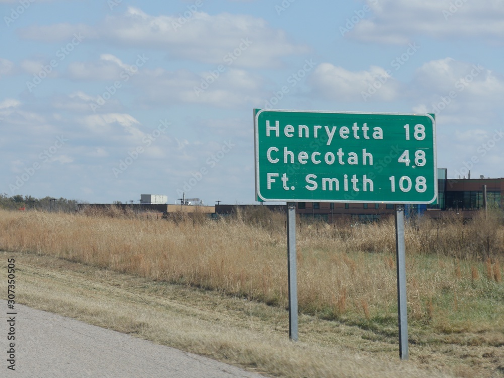 Medium close up of roadside sign with distances to Henryetta, Chekotah and Fort Smith at Interstate 240 in Oklahoma.