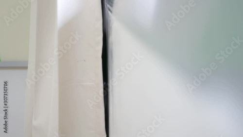 Little Asian baby girls, sisters, 2 and 3 years old, playing peekaboo / hide and seek behind a curtain at a hospital, as the little one visiting her older sister - childhood