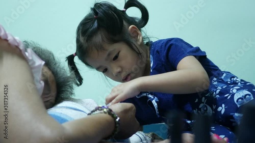 Little baby girl, 42 months old, enjoys painting her sleeping grandmother's finger nails at home - childhood exploration and curiosity