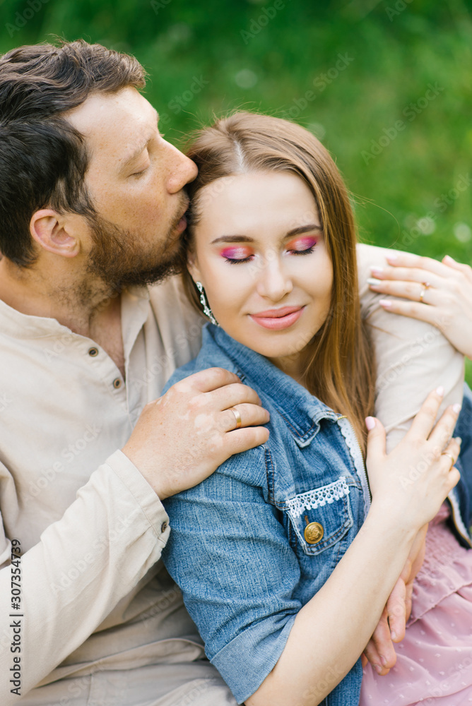 Portrait of a couple in love. The guy kisses the girl on the temple and hugs her. Valentine's day. Love and happiness in a relationship Portrait of a couple in love. The guy kisses the girl on the temple and hugs her. Valentine's day. Love and happiness in a relationship