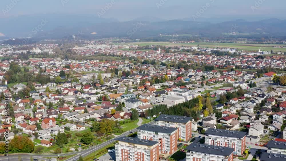 Orbiting aerial shot over the large city of Domzale, Slovenia, during the daytime with residential houses and buildings below Orbiting aerial shot over the large city of Domzale, Slovenia, during the daytime with residential houses and buildings below
