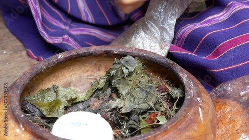 Hands of an old lady preparing betel leaves, nuts, and limestone paste in an old grungy bowl before putting them into her mouth - Betel chewing in Thailand