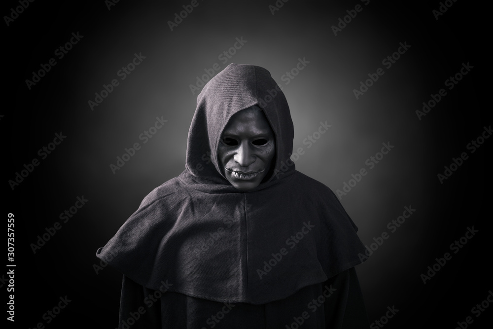 Scary figure in hooded cloak with mask 