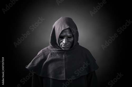 Scary figure in hooded cloak with mask 