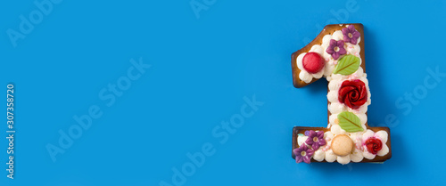 Number one cake decorated with flowers and cookies on blue background. Panorama view