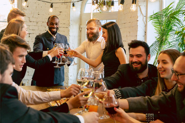 Happy co-workers celebrating while company party and corporate event. Young caucasian people in business attire cheering, laughting. Concept of office culture, teamwork, friendship, holidays, weekend.