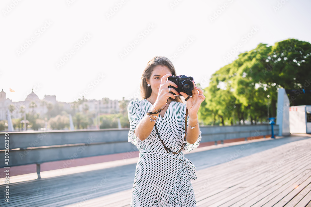 Beautiful woman holding modern equipment for photography hobby and making new pictures of city landscape during holidays in Spain, charming hipster girl taking images via camera for amateurs