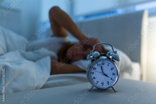 young beautiful woman at home bedroom lying in bed late at night trying to sleep suffering insomnia sleeping disorder or scared on nightmares looking sad worried and stressed