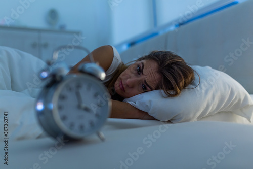 Woman with insomnia lying in bed with open eyes. Girl in bed suffering insomnia and sleep disorder thinking about his problem at night photo